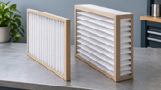 Two clean pleated HVAC filters with different depths displayed side by side on a workbench.