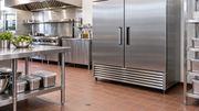 Commercial kitchen refrigerator with closed doors and an unobstructed lower ventilation grille beside a stainless steel preparation table.